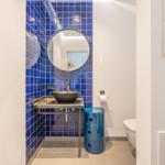Badezimmer mit blauen Fliesen, runden Spiegel und Waschtisch