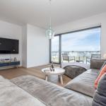 Wohnzimmer mit Sofa, Fernseher und Balkonansicht