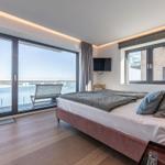 Schlafzimmer mit Blick auf Wasser und Balkon. Bett, TV und moderne Beleuchtung.