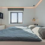 Schlafzimmer mit Bett, Fenster und TV an der Wand.