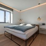 Schlafzimmer mit Bett, Fenster und zwei Hängelampen.