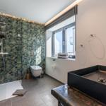 Badezimmer mit Dusche, Waschbecken und Fenster