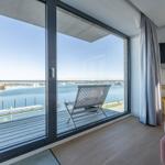 Zimmer mit Blick auf Hafen und Bootshäfen über große Glastüren.