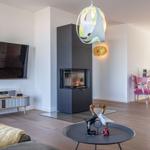 Wohnbereich mit Kamin, Fernseher und pinkem Sitzbereich.
