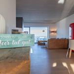 Wohnbereich mit Küchenzeile, Sofa und Blick aufs Meer.
