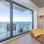 Zimmer mit Balkon und Blick auf Wasser. Gelber Deckenbezug auf Sofa.