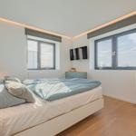 Schlafzimmer mit Bett, Fenstern und gelbem Schrank.