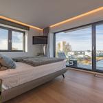 Schlafzimmer mit großem Bett und Blick auf Wasser und Balkon.