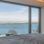 Schlafzimmer mit Blick aufs Wasser und Terrasse mit Stuhl.