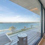 Terrasse mit Sitzgelegenheit und Blick auf Wasser und Ufer.