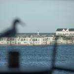 Wohnungen am Wasser mit Leuchtturm im Hintergrund