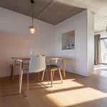 Essbereich mit Tisch, Stühlen und rotem Kühlschrank. Durchgang zur Terrasse mit Glasfront.