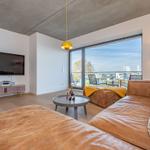 Wohnzimmer mit Ledersofa, Fernseher und Balkonblick.
