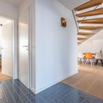 Eingangsbereich mit Treppenhaus, Schlafzimmer und Essbereich mit orangefarbener Stuhle.