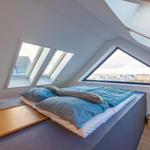 Schlafzimmer mit Dachfenstern und Blick auf die Umgebung.