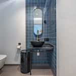 Badezimmer mit blauen Fliesen, Waschbecken und Spiegel