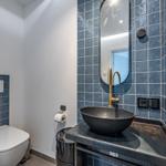 Badezimmer mit blauen Fliesen, Waschbecken und Spiegel