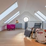 Dachgeschosszimmer mit Dachschrägen, Fenstern und Möbeln.