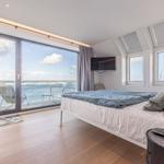 Schlafzimmer mit Blick aufs Wasser und Balkon mit Stuhl.