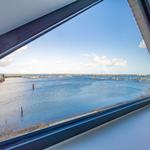 Aus dem Fenster sieht man einen Hafen mit Booten und einem blauen Himmel.