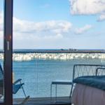 Blick auf Wasser und weiße Häuser vom Balkon mit Stuhl und Tisch.