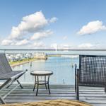 Terrasse mit Stühlen und Tisch bietet Blick auf Wasser und Häuser.
