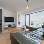 Wohnzimmer mit Sofa, Fernseher und Blick auf den Balkon.