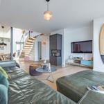 Wohnzimmer mit Sofa, Fernseher und Surfbrett an der Wand.