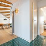 Eingangsbereich mit Holzboden, grünen Fliesen und Blick in Wohn- und Schlafzimmer.