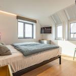 Schlafzimmer mit Dachschrägen, Bett, TV und Fenster.
