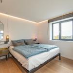 Schlafzimmer mit Bett, Fenster und moderner Beleuchtung.