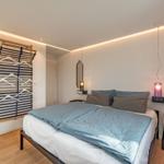 Schlafzimmer mit Bett, Kleiderständer und modernen Lampen.