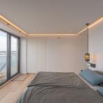 Schlafzimmer mit Blick auf Wasser und Terrasse mit Liege.