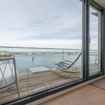 Terrasse mit weißem Sofa und Schaukelstuhl über Wasserblick.