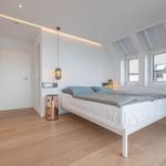 Schlafzimmer mit Dachschrägen, Fenstern und Bett.