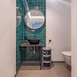 Badezimmer mit blauen Fliesen, runden Spiegel und Waschbecken