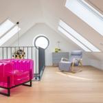Dachgeschosszimmer mit pinkem Sessel, Sitzgelegenheit und Holzboden.