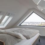 Schlafzimmer mit Dachfenster und Blick auf Wasser und Gebäude.