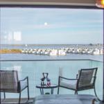 Balkon mit Sitzgelegenheiten und Blick auf Wasser und Häuser.