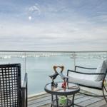 Terrasse mit Sitzgelegenheiten und Blick auf Wasser und Ferienhäuser.