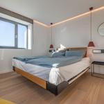 Schlafzimmer mit Doppelbett, Fenster und moderner Beleuchtung.