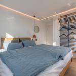 Schlafzimmer mit Bett, Kleiderständer und Stuhl.
