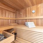 Sauna mit Holzbank, gefalteten Handtüchern und Steinbehälter.
