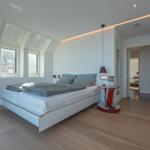 Schlafzimmer mit Dachfenstern, Bett und Tisch.