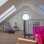 Dachgeschosszimmer mit Sitzgelegenheit und runden Fenster