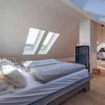 Schlafzimmer mit Dachfenstern und Blick in Wohnbereich