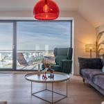 Wohnzimmer mit Blick aufs Meer, Sofa, Sessel und runder Tisch.