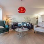 Wohnzimmer mit Sofa, Sesseln und Blick aufs Wasser.