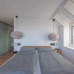 Schlafzimmer mit Doppelbett, zwei hängenden Lampen und Schlupftür.
