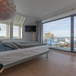 Schlafzimmer mit Balkonblick auf Wasser und Gebäude
